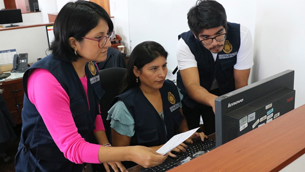 Trabajadores del ministerio público viendo computadora