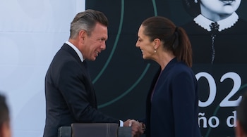 Un hombre de traje negro y una mujer de chaqueta azul marino estrechan las manos frente a un fondo gráfico con un retrato histórico