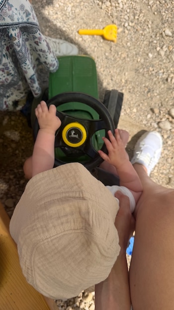 Lando López maneja un tractor de juguete con el cuidado de Daniela Christiansson, su mamá