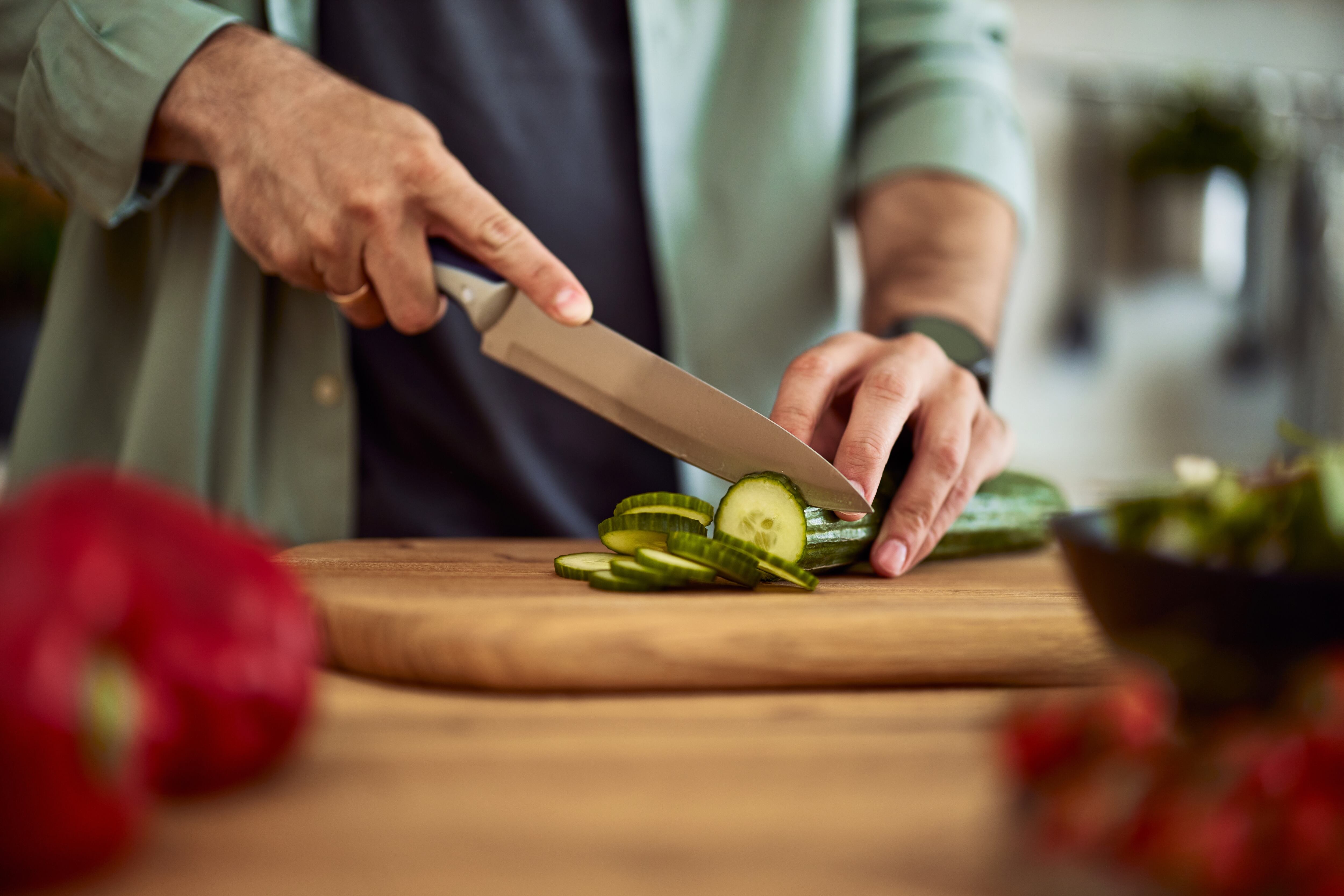 Un hombre corta unas rodajas de pepino (Shutterstock España)