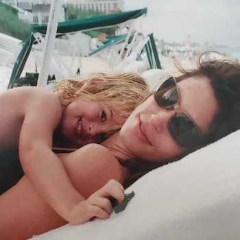 Cindy Crawford con gafas de sol acostada en una reposera junto a su hija Kaia Gerber en una playa con sombrillas de fondo
