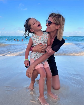 Eugenia Tobal, su pareja y su hija posan sonrientes frente al Castillo de Cenicienta en Walt Disney World, con un cielo azul claro de fondo