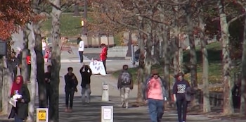 Personas caminan a lo largo de un sendero arbolado dentro de un campus universitario