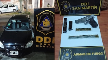 Un automóvil negro junto a un cartel institucional y, a la derecha, una pistola plateada con dos cargadores y varias balas