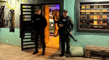 Dos efectivos de Gendarmería con uniforme oscuro y chaleco antibalas custodian la puerta abierta de una vivienda