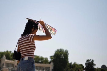 Una chica se protege del sol con un abanico en el parque de El Retiro de Madrid. (EFE/ Marcos Villaoslada)
