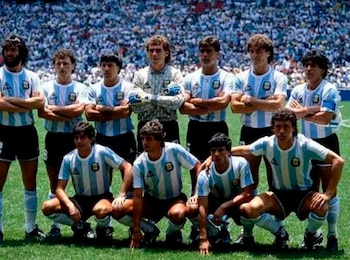 Once futbolistas con camiseta a rayas celestes y blancas posan en un campo de juego frente a un público en un estadio