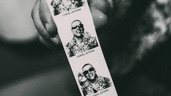 Primer plano de una mano que sostiene una tira de fotos en blanco y negro de un hombre con gafas oscuras que sonríe y hace gestos