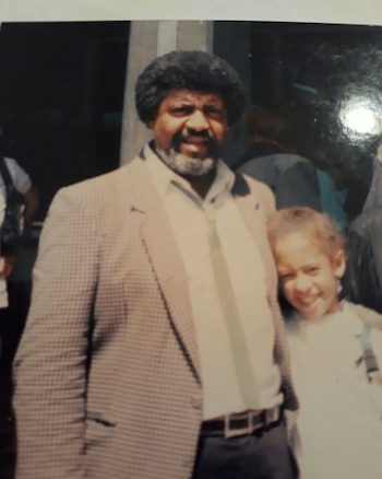 Un hombre con saco y corbata posa junto a una niña sonriente en una fotografía