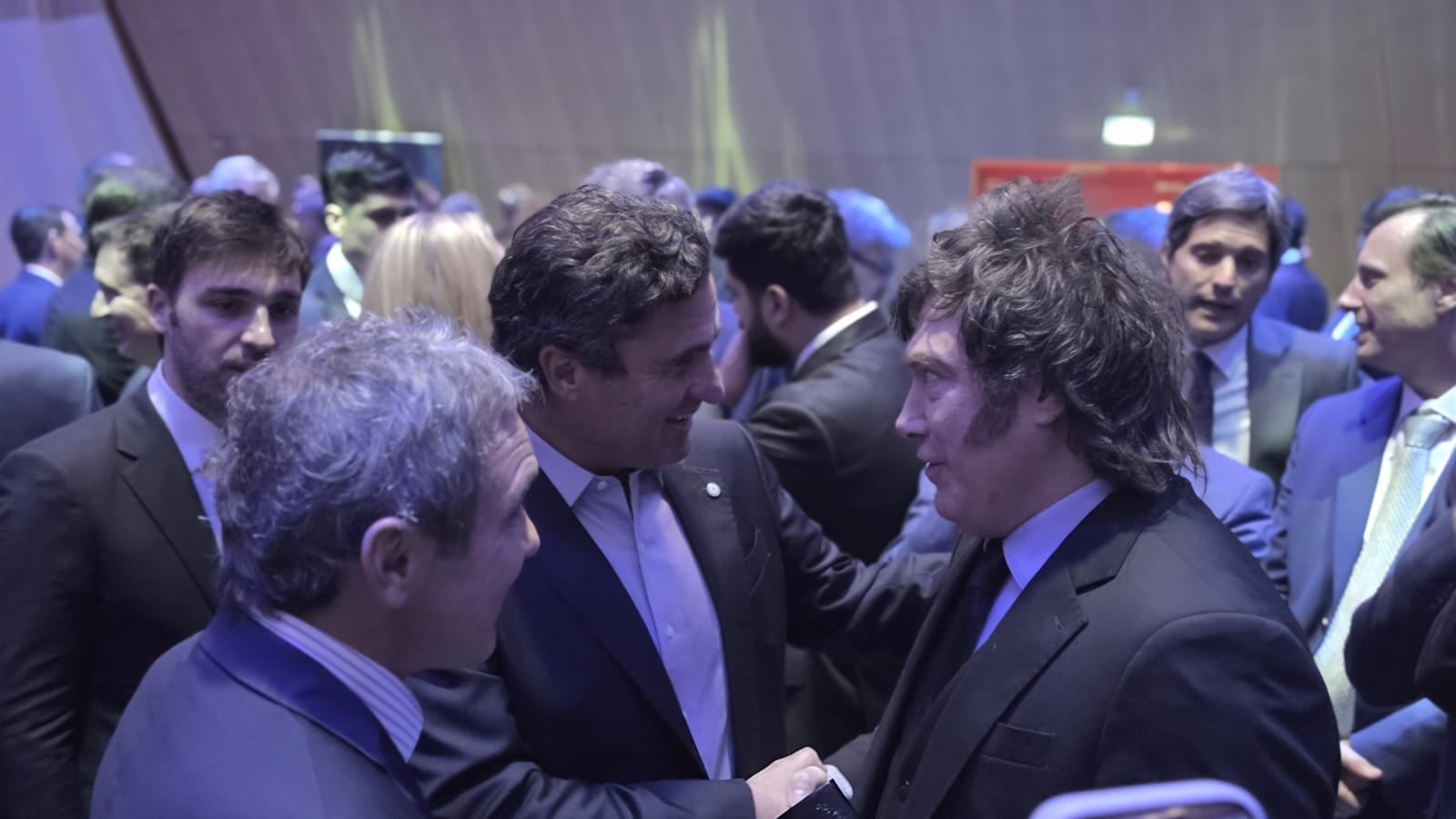 El presidente Javier Milei conversa con empresarios y miembros de su delegación durante un encuentro sobre inversiones en París.