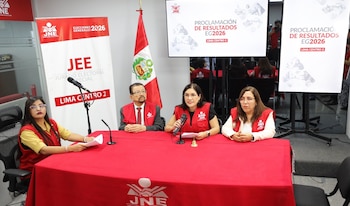 Quatro funcionários do JNE, vestidos de vermelho, estavam sentados numa mesa vermelha com um microfone. No fundo, a tela aparece