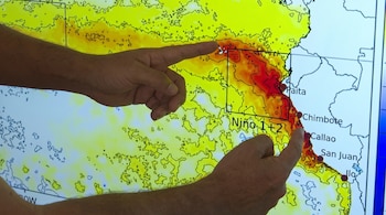 Dos manos apuntan a un mapa de la costa peruana con anomalías de temperatura del mar en amarillo y rojo. Se ven las ciudades Paita, Chimbote, Callao, San Juan y la zona Niño 1+2