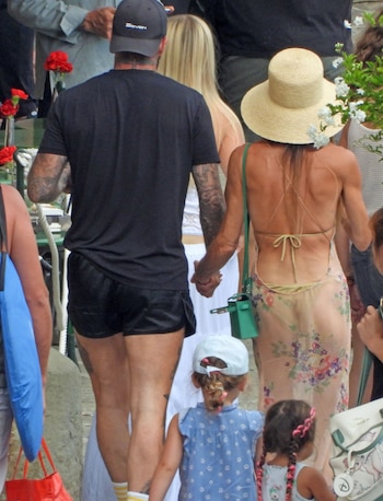 Hombre, mujer, dos niñas, gorra negra, camiseta negra, shorts negros, calcetines, sombrero de paja, vestido floral, bolso verde, gorra blanca, trenzas, flores