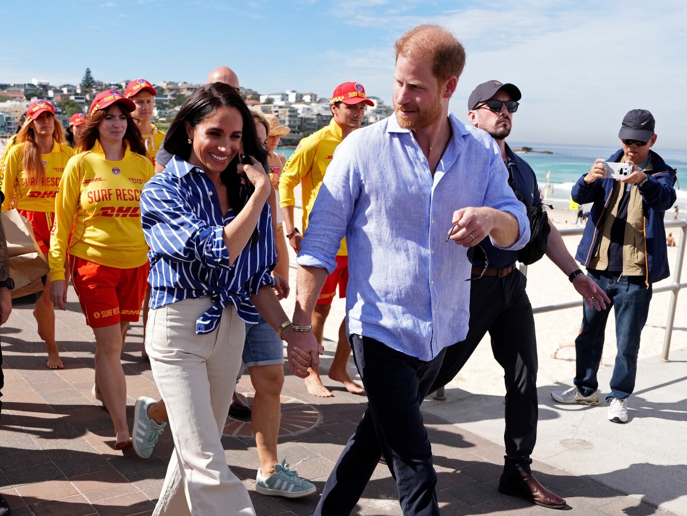 El príncipe Harry y Meghan, los duques de Sussex, caminan por el paseo marítimo tras reunirse con socorristas voluntarios del Bondi Surf Bathers' Life Saving Club, durante una visita a la playa de Bondi, en Australia, 2026. (Jonathan Brady/Pool Photo via AP, archivo)