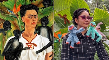 Pintura de Frida Kahlo con cuatro monos negros y hojas grandes al lado de una mujer con gafas, camisa a cuadros y cuatro monos de peluche.