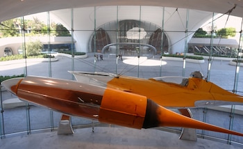 Una nave espacial amarilla y de metal pulido cuelga dentro de un amplio vestíbulo con paredes de vidrio
