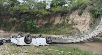 El vehículo pick-up quedó volcado con las llantas hacia arriba tras caer desde una altura considerable al colapsar los cables del puente (Cortesía @ConfidencialHN).