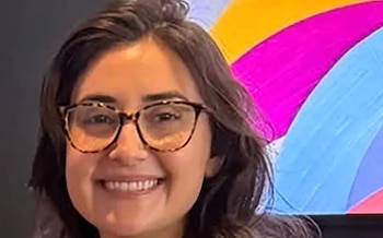 Mujer joven sonriente con cabello oscuro y gafas de carey. Fondo difuminado con franjas de colores vivos: amarillo, rosa y azul