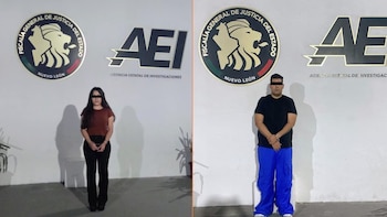 Dos personas esposadas, una mujer con blusa café y un hombre con camiseta negra, de pie frente a los logos de la Fiscalía de Nuevo León y la AEI