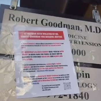 Póster blanco con texto sobre Robert Goodman, M.D., adherido a un cartel de consultorio médico. Contiene un código QR