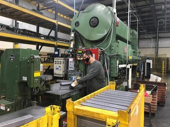 Imagen de archivo de un trabajador operando maquinaria industrial en una fábrica.