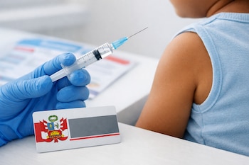 Mano con guante azul sostiene jeringa con aguja. Brazo de niño con camiseta celeste. Credencial plástica con escudo de Perú sobre mesa.