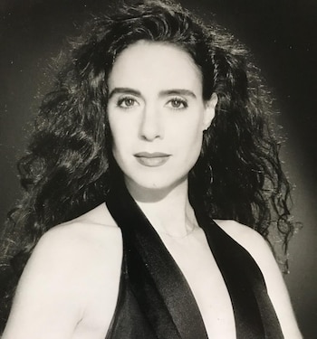 Retrato en blanco y negro de una mujer con el cabello largo y rizado que viste una prenda oscura con escote pronunciado