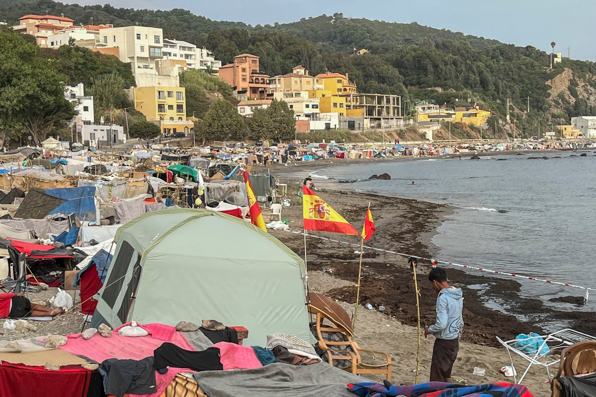 Vista de las tiendas de campaña y construcciones improvisadas por los migrantes asentados en la playa del Trampolín, esta mañana en Ceuta (EFE/ Reduan)