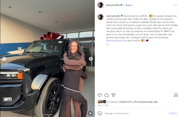 Valery Revello sonriente abraza a su hija frente a una camioneta SUV negra nueva con un lazo rojo, dentro de un concesionario de automóviles