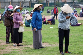 Mujeres vietnamitas esperan disciplinadamente, en