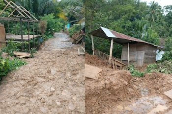 Camino de tierra cubierto de lodo, estructuras de madera, una casa con techo de metal y vegetación densa.