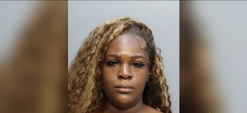 Retrato de frente de una mujer con cabello rizado y reflejos rubios sobre un fondo gris