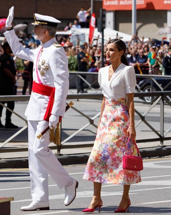 En 2023 los reyes se desplazaron hasta Granada, donde Letizia quiso hacer un guiño a la comunidad autónoma de la mano de su estilismo. Para este día apostó por una primaveral falda con estampado floral del andaluz José Hidalgo. La combinó con una blusa blanca drapeada, hombros marcados y escote cruzado de Boüret, una firma gallega. Para terminar apostó por unos zapatos de tacón destalonados, en fucsia, y un bolso de piel de cocodrilo.