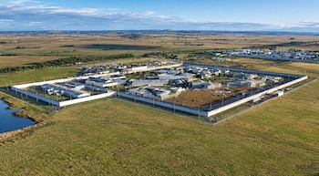 Vista aérea de un recinto penitenciario rodeado de muros altos, varios pabellones interiores, un estanque y campos abiertos