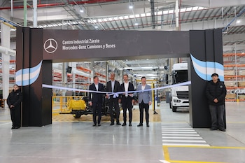 Cuatro hombres cortan una cinta celeste y blanca frente a un cartel que dice "Centro Industrial Zárate Mercedes-Benz Camiones y Buses". Hay un camión blanco en la fábrica