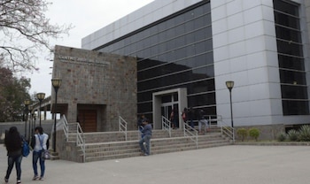 Exterior del Centro Judicial Banda con fachada de piedra y ventanales oscuros, escalinatas, personas en la entrada, árboles y faroles