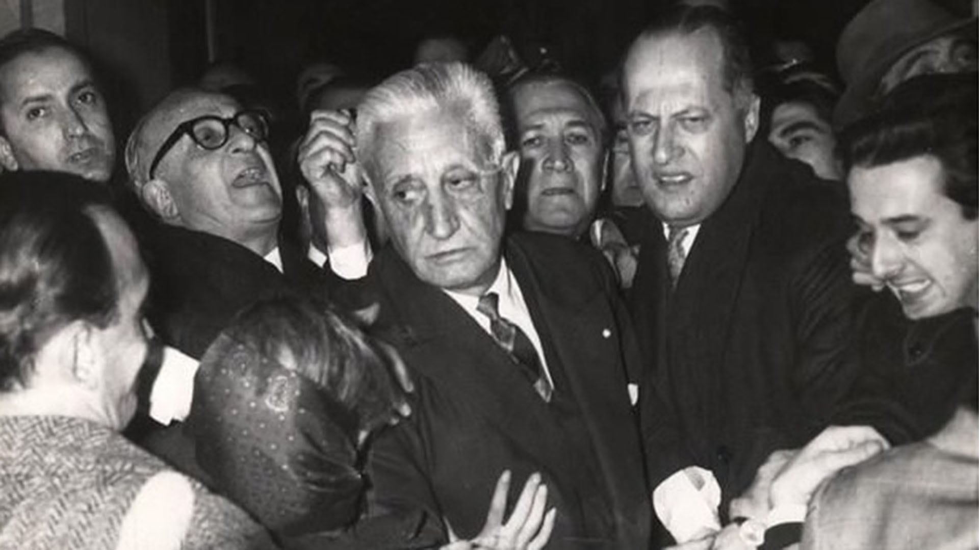 El presidente Arturo Illia dejando la casa de gobierno en medio de sus colaboradores y amigos