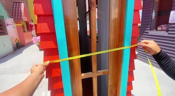 Una persona con el metro midiendo la casa