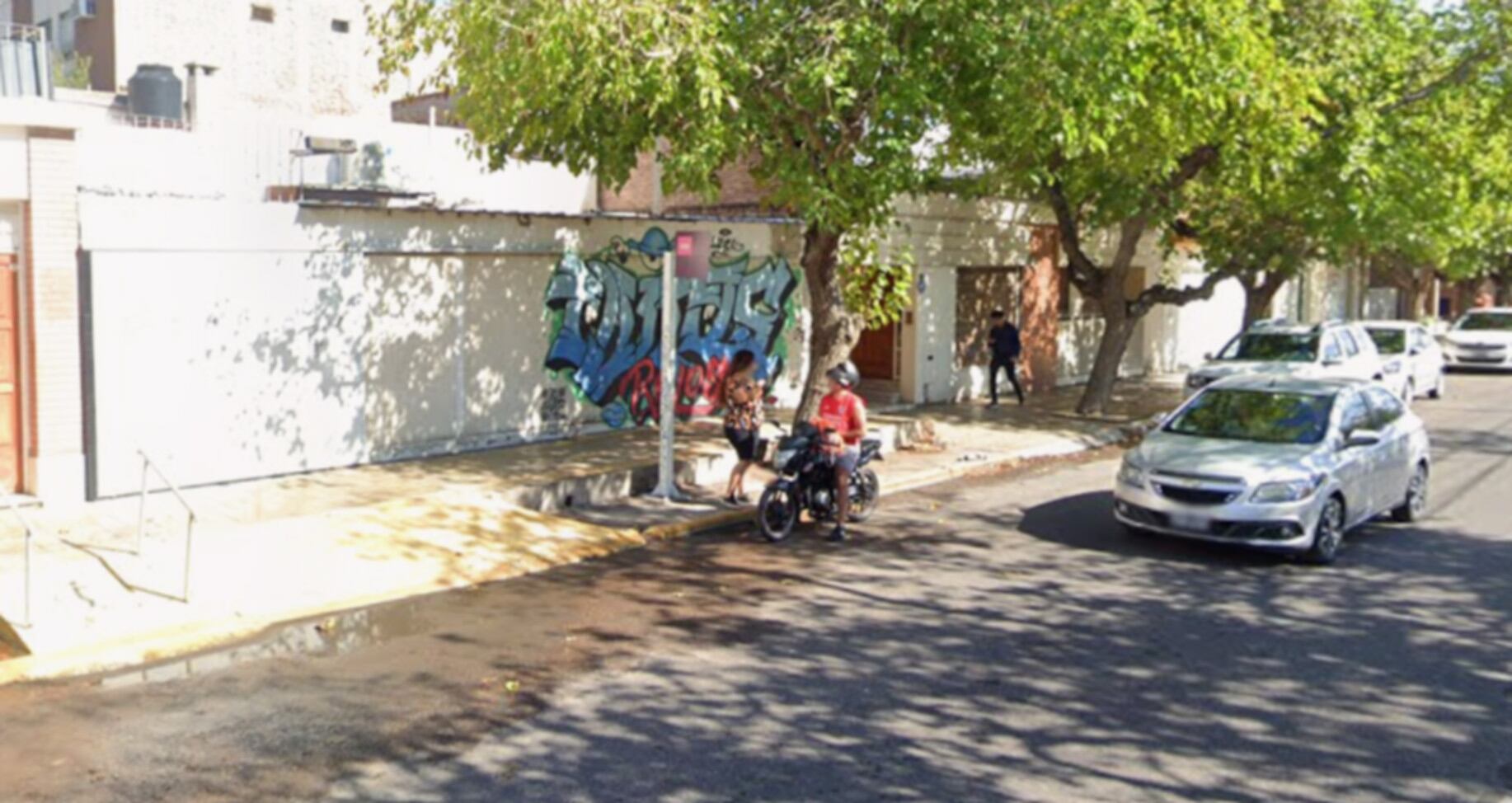 Un sector de una calle en Catamarca muestra un edificio con grafitis y personas en la acera, en un contexto de un asalto a un comercio. (Google Maps)
