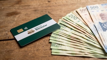 Tarjeta de débito verde oscuro del Banco del Bienestar con chip y símbolo contactless junto a billetes de 200 y 500 pesos mexicanos sobre madera.