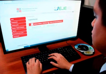Manos de una persona escribiendo en un teclado frente a un monitor con el sitio web del Poder Judicial de Perú. Hay un ratón y una alfombrilla sobre un escritorio