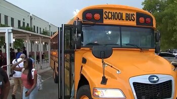 Autobús escolar amarillo con la puerta abierta frente a un edificio con personas, incluyendo estudiantes, en el sur de Florida