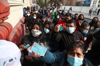 Miembros de la comunidad peruana residente en Chile muestran sus documentos de identidad antes de depositar su voto en un colegio público, en Santiago (REUTERS/Ivan Alvarado)