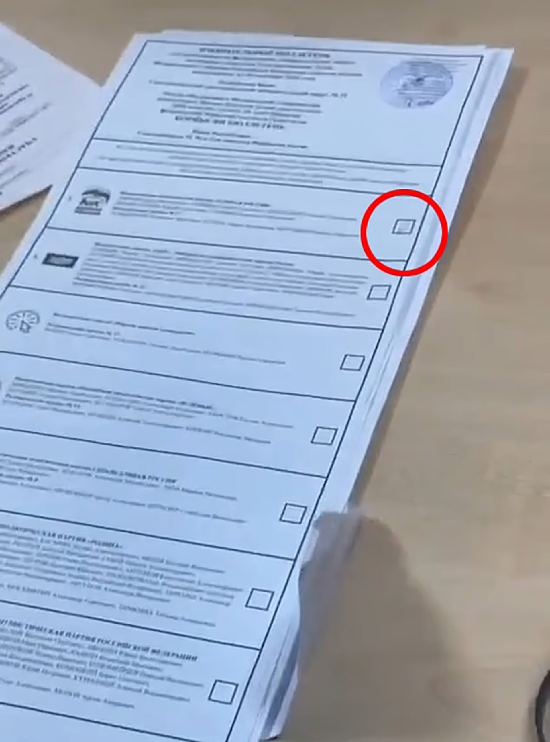 Una pila de papeletas oficiales en idioma ruso presenta una casilla resaltada en el contexto de denuncias por fraude electoral.