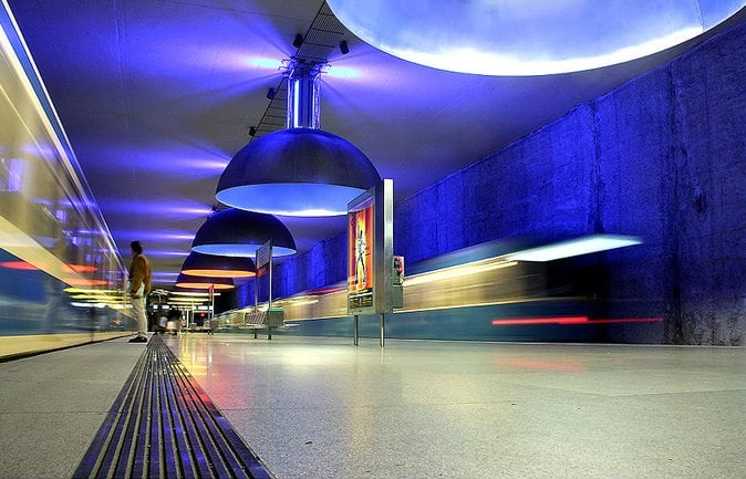 Once lámparas industriales de gran tamaño proyectan luces rojas, amarillas y azules sobre los andenes de Westfriedhof, una estación de la línea U1 del metro de Múnich