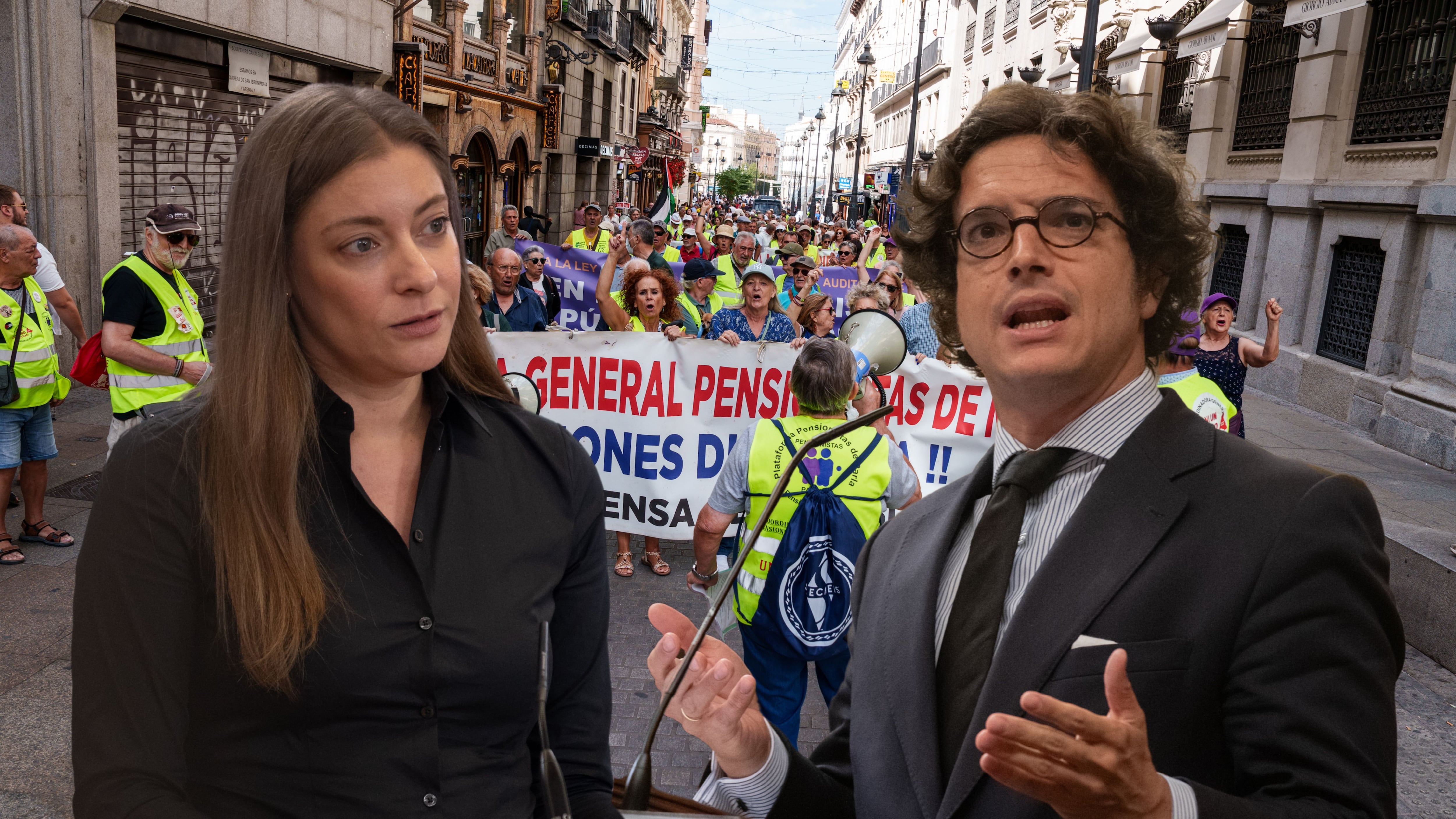 Ester Muñoz y José María Figaredo. De fondo, una manifestación por las pensiones. (Europa Press)