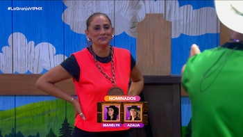 Azalia lleva un chaleco rojo en un set con un gráfico en pantalla que señala a las nominadas Manelyk y Azalia
