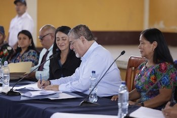 Bernardo Arévalo posa junto a personas con indumentaria indígena ante una pancarta de bienvenida en Guatemala