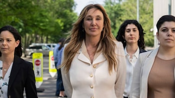 Nicole Daedone, una mujer con cabello largo rubio, posa en primer plano con una chaqueta color crema, flanqueada por otras mujeres en el exterior