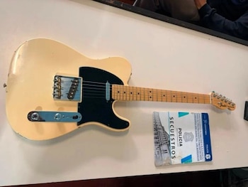 Guitarra eléctrica Fender Telecaster crema con pickguard negro, diapasón de madera clara, junto a un formulario policial de secuestro sobre una mesa blanca